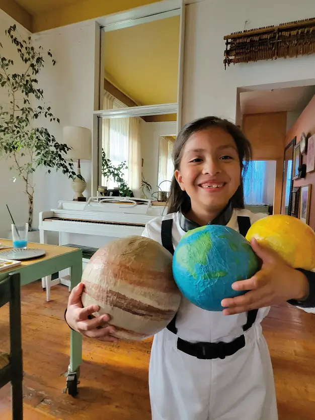 リビングで惑星の模型を手に微笑んでいる子ども。